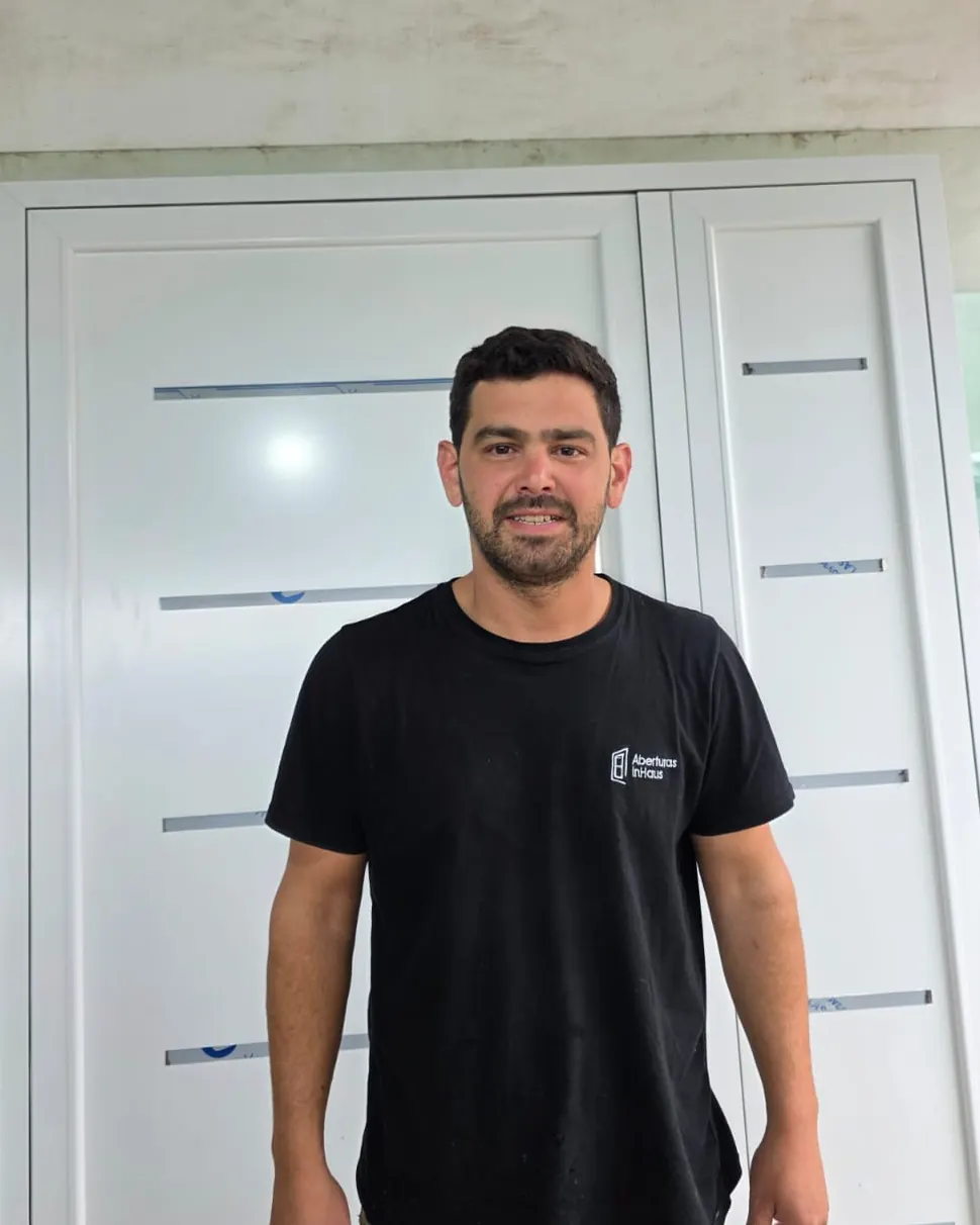 Lautaro, de InHaus, en el taller, con la remera de la marca delante de una puerta blanca